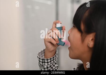 Asthmatisches junges Mädchen, das einen Asthma-Inhalator benutzt, während es an Asthma in der Toilette zu Hause leidet. Stockfoto