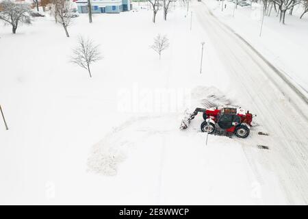 Reinigung von Schnee von den Straßen nach einem starken Schneefall. Der Traktor reinigt die Schneeansicht von oben. Stockfoto