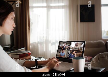 Lächelnd junge asiatische Frau Video anrufen auf Laptop. Rückansicht Foto Student Blick auf Computer-Bildschirm beobachten Webinar oder tun Video-Chat mit Webcam. Stockfoto