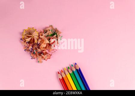 Geschärfte Buntstifte und herzförmige Bleistiftspäne in pastellrosa Farbe. Rainbow- oder LGBT-Stifte. Dekoration für den Valentinstag. Draufsicht Stockfoto