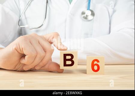 Arzt empfiehlt die Einnahme von Vitamin B12. Arzt spricht über die Vorteile von Vitamin B6. Vitamin - Gesundheitskonzept. B6 Alphabet auf Holzwürfel. Hand hält ein Stockfoto