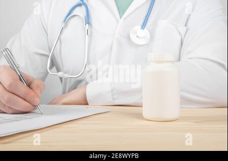 Arzt verschreibt Medikamente. Anweisung, Pillen richtig zu nehmen. Pharmaindustrie. Leere weiße Plastikflasche Behälter Drogen. Arzt, Hand Hol Stockfoto