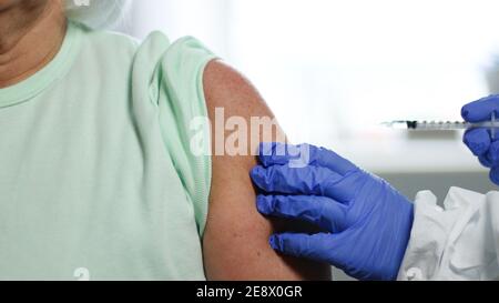 Weibliche Arzt oder Krankenschwester Latex-Gummihandschuhe halten Spritze geben Schuss oder Impfstoff auf die Schulter eines Patienten. Impfung und Prävention gegen Grippe oder Viruspandemie. Stockfoto