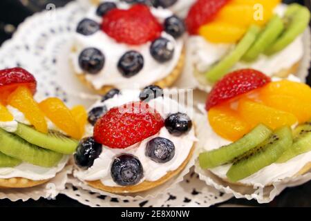 Cremige Kuchen mit frischen Früchten und Beeren. Süßsahnedessert mit Mandarinen, Kiwi, Erdbeere und Heidelbeeren Stockfoto