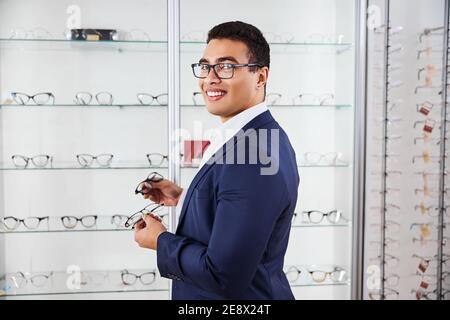 Lächelnder Käufer hält zwei Paar Gläser in den Händen Stockfoto