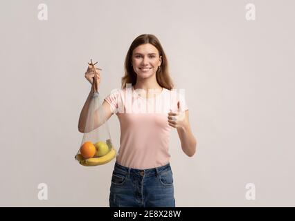 Lächelnd Frau Holding Waschbar Mesh Net String Einkaufstasche Mit Bio-Früchte Stockfoto