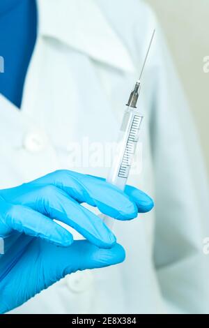 Ärztin in der Hand hält eine Spritze mit einer Nadel in einem Winkel. Konzept der Medizin, Impfung. Vertikales Foto Stockfoto