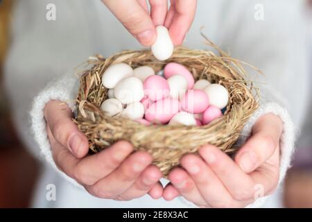 Frauenhände bieten Ostermandeln im Vogelnest an Stockfoto