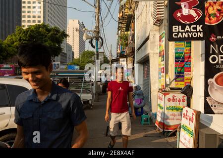 Yangon, Myanmar - 19. Dezember 2019: Fußgänger, die auf dem Bürgersteig der Sule St, voll von Verkehr und Straßenverkäufern, in der Nähe der Sule Paya Road Pedest Stockfoto