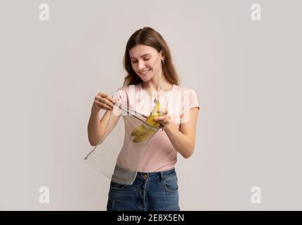 Null Verschwendung Einkaufen. Happy Millennial Woman Putting Bananen In Wiederverwendbare String-Tasche Stockfoto