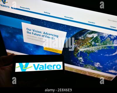 Person, die Smartphone mit Logo des US-petrochemischen Unternehmens Valero Energy Corporation auf dem Bildschirm vor der Website hält. Konzentrieren Sie sich auf die Telefonanzeige. Stockfoto