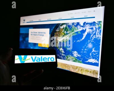 Person mit Mobiltelefon und Logo des US-amerikanischen petrochemischen Unternehmens Valero Energy Corporation auf dem Bildschirm vor der Webseite. Konzentrieren Sie sich auf die Telefonanzeige. Stockfoto