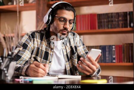 Indian Male Student Mit Smartphone Learning Sitzen In Der Bibliothek Stockfoto