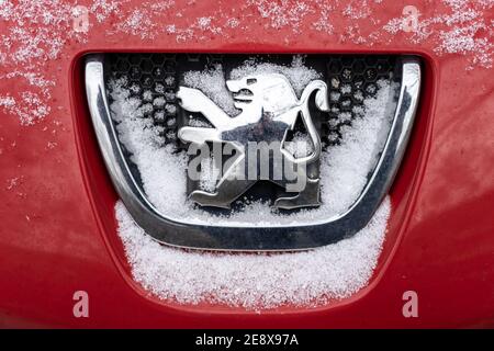 BERLIN - 16. JANUAR 2021: Silbernes Peugeot-Emblem auf der Motorhaube des Autos mit Schnee bedeckt. Stockfoto