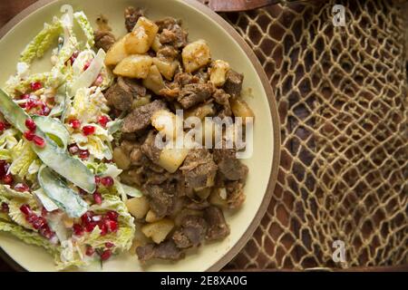 Venisenstücke von einem Damhirsch, die mit gewürfeltem Lamm gebraten und mit Kartoffeln und Knoblauch gekocht wurden. Hausgemacht und serviert mit einem sw Stockfoto