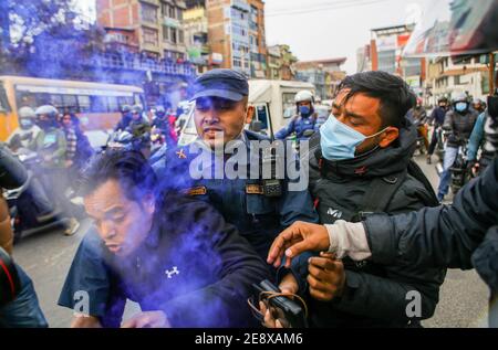 Kathmandu, Nepal. Februar 2021. Polizeibeamte halten einen Protestanten fest, der während der Demonstration ein brennendes Fackeln auslöst.Anhänger der nepalesischen Kommunistischen Partei protestierten gegen die Auflösung des parlaments.Nepals Präsident Bidya Devi Bhandari stimmte der Auflösung des parlaments zu und erklärte die Parlamentswahlen in zwei Phasen am 30. April und 10. Mai. Kredit: SOPA Images Limited/Alamy Live Nachrichten Stockfoto