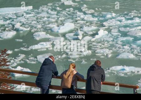 Eis Drift am Gletscher Perito Moreno.Gruppe von Touristen beobachten Bewegung von bläulichen Eisschollen, die auf dem türkisfarbenen Argentino See treiben Wasserhintergrund Stockfoto