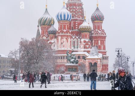 Schneefall in Moskau.Menschen, die Winterwetter genießen, wandern auf dem Roten Platz neben der Basilius-Kathedrale in starkem Schneesturm auf und ab. Stockfoto