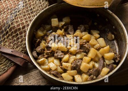 Venisenstücke von einem Damhirsch, die mit gewürfeltem Lamm gebraten und mit Kartoffeln und Knoblauch gekocht wurden. Als Nächstes in einer Kupferpfanne Stockfoto