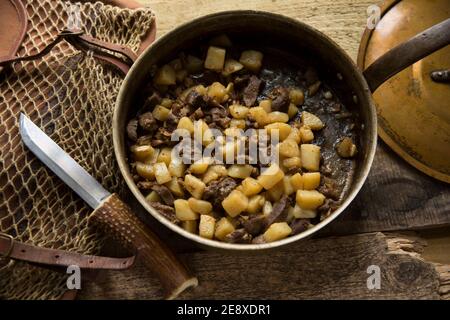 Venisenstücke von einem Damhirsch, die mit gewürfeltem Lamm gebraten und mit Kartoffeln und Knoblauch gekocht wurden. Als Nächstes in einer Kupferpfanne Stockfoto