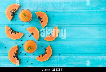Papaya-Scheiben. Blauer Hintergrund von Holzplanken. Speicherplatz kopieren. Draufsicht. Stockfoto