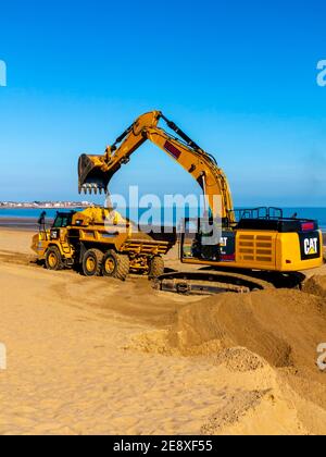 Mechanischer Bagger und Erdschlepper Entfernung Sand vom Strand in Colwyn Bay Conway Wales Großbritannien nach schweren Winterstürmen verdrängte den Sand. Stockfoto