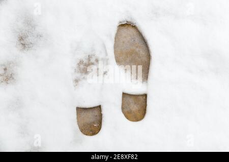 Nahaufnahme von zwei Fußabdrücken in schneebedeckter Pflasterplatte Draußen an einem kalten Wintertag Stockfoto