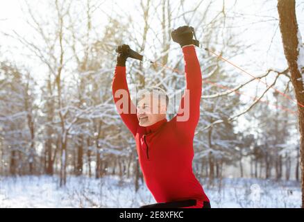 Funktionelles Training im Freien. Reifer Mann mit Aufhängebänder, um Oberkörpermuskeln im verschneiten Winter Park trainieren Stockfoto
