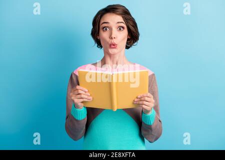 Foto-Porträt von schockiert beeindruckt weiblichen Studenten hält gelbe Buch Isoliert auf lebhaftem blauem Hintergrund Stockfoto