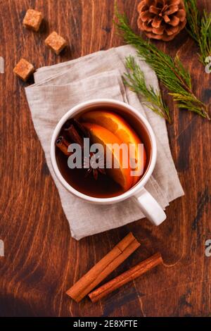 Tasse heißen Tee mit Orange und Gewürzen auf rustikalem braunen Hintergrund. Nahaufnahme Stockfoto