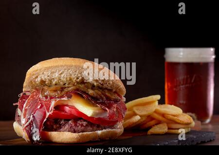 Nahaufnahme eines leckeren Burger in der Nähe eines Bierglases Auf einem dunklen Hintergrund Stockfoto