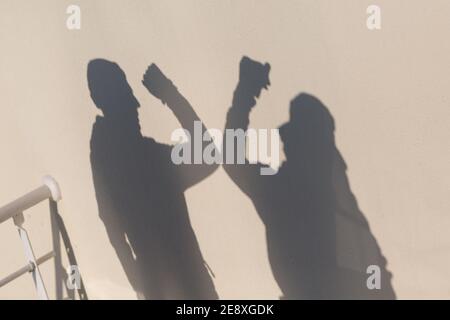 Ellenbogen Stoß Sicherheit Gruß von zwei Menschen Schatten an der Wand des Coronavirus COVID-19 Pandemie. Neuer Normalwert. Stockfoto