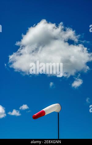 Windrichtungsanzeiger unter einem hellblauen Himmel mit flauschigen Wolken an einem sonnigen Tag Stockfoto