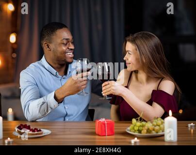Liebevoll Gemischtes Paar Mit Romantischem Abendessen Im Restaurant, Wein Trinken Und Lächeln Stockfoto