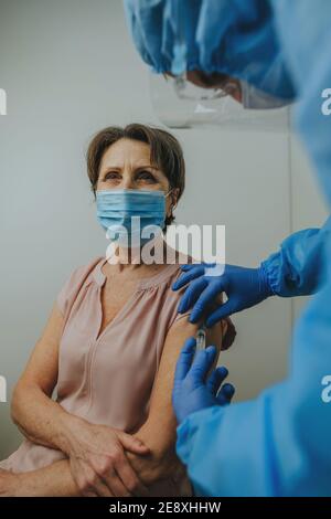 Arzt in schützenden Overall und Handschuhe, die COVID-19 Impfung Stockfoto