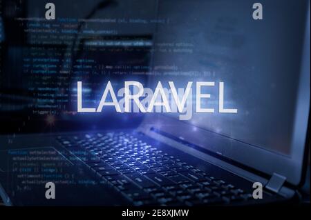 Laravel Inschrift gegen Laptop und Code Hintergrund. Technologiekonzept. Stockfoto