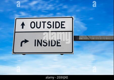 Straßenschild mit Worten außen und innen. Weiße zwei Straßenschilder mit Pfeil auf Metallmast. Richtungsstraße, Kreuzung Straßenschild, zwei Pfeil auf blauen sk Stockfoto