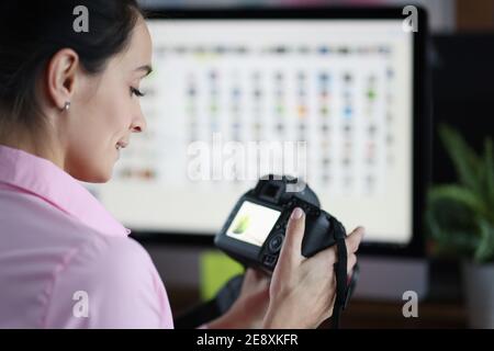 Junge Frau, die Kamera in den Händen hält und Fotos ansieht Stockfoto