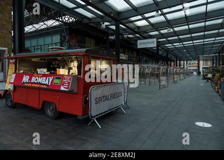 London, Großbritannien. Februar 2021. Ein indischer Street-Food-Händler vor leeren Marktständen am Spitalfields Market in East London, da die Sorge über die Schwere einer südafrikanischen Covid-19-Variante in Großbritannien weiter anhält. Die britische Regierung hat auch gerade angekündigt, dass 9,2 Millionen Menschen geimpft wurden. Vor der Pandemie würden Marktstände geöffnet sein und die Restaurants mit Einheimischen und Feinschmeckertouristen überfüllt sein. Kredit: Stephen Chung / Alamy Live Nachrichten Stockfoto