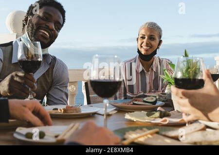 Junge multirassische Freunde tun Vorspeise und trinken Rotwein auf Haus Terrasse während Sonnenuntergang Zeit Stockfoto