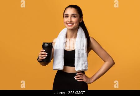 Sportliche Frau hält Shaker mit Protein oder Wasser Stockfoto