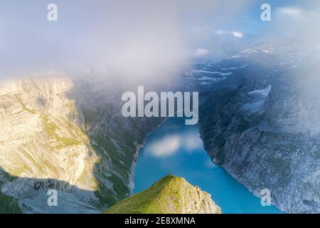 Wanderer auf Bergrücken bewundern den nebligen Sonnenuntergang über dem See Limmernsee, Luftbild, Kanton Glarus, Schweiz Stockfoto