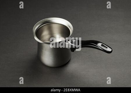 Silberner Kaffee-turk-Topf mit schwarzem Griff auf schwarzem Hintergrund. türkische Kaffeemaschine Stockfoto