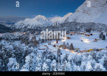 Schneebedeckter Wald auf den Bergen oberhalb der Chiesa Bianca in der Abenddämmerung, Maloja, Bregaglia, Graubünden, Engadin, Schweiz Stockfoto