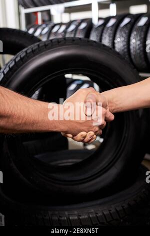 Verkäufer und Kunde schüttelt sich die Hände in Auto-Service-Shop, Mann machte Wahl, Kauf Autoreifen für den Winter Stockfoto