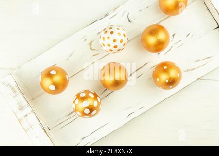 Ostern festliche Dekoration. Draufsicht auf Ostereier mit goldener Farbe auf weißem Holztablett. Verschiedene gepunktete Designs Stockfoto