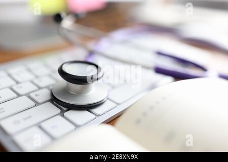 Stethoskop liegt auf Computer-Tastatur in Arztpraxis Nahaufnahme Stockfoto