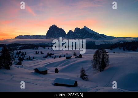 Sonnenaufgang über Langkofel und Langkofel und schneebedeckte Hütten, Seiser Alm, Dolomiten, Südtirol, Italien Stockfoto