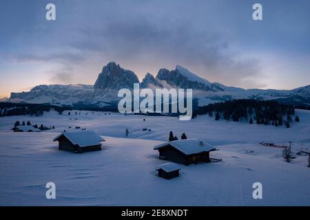 Schneebedeckte Berghütten mit Langkofel und Langkofel im Hintergrund bei Sonnenaufgang, Seiser Alm, Dolomiten, Südtirol, Italien Stockfoto