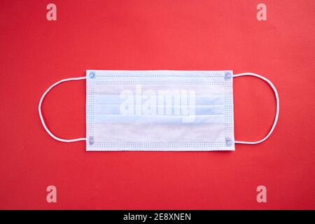 Medizinische Gesichtsmaske isoliert auf rotem Hintergrund. Coronavirus Epidemie Konzept. Sicherheitsbedarf Stockfoto